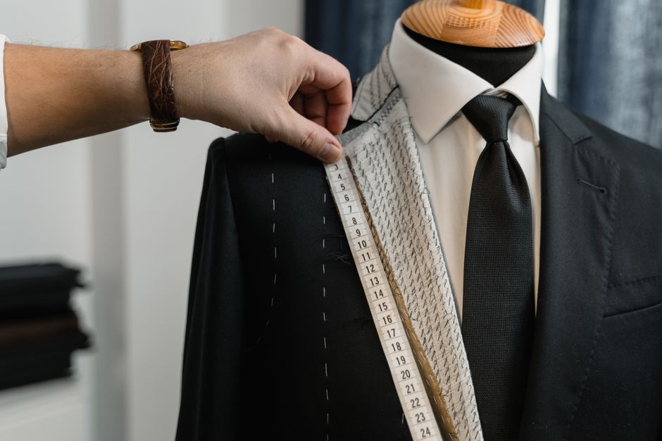 A tailor carefully sewing dark fabric by hand