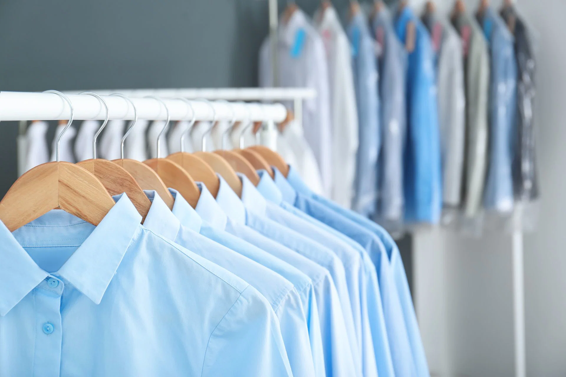 A neat row of freshly pressed blue shirts on hangers